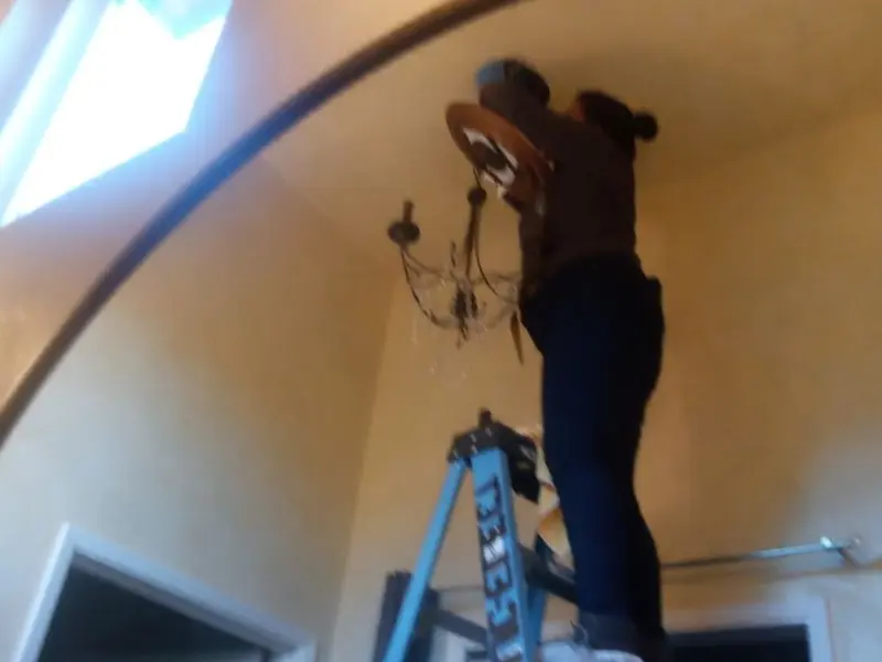 Electrician installing a chandelier in a Sun Lakes residence